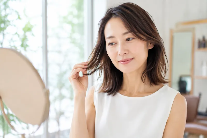 40代の日本人女性が髪をいたわるイメージ